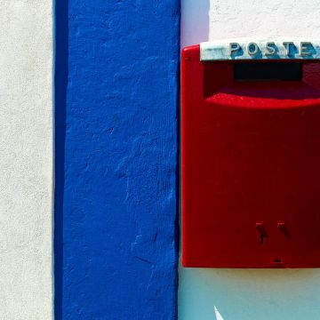 Hausfassade mit rotem Briefkasten und blau weißem Mauervorsprung