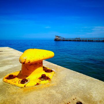 Gelber Ankerpoller am Hafen mit marinblauem Meer und tiefblauem Himmel