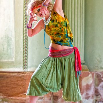 Model in Tanzpose in grüner Berberhose und Sandaletten