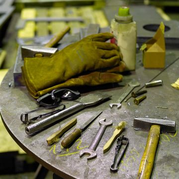 Handwerkszeug auf einem Werzeugtisch aus Metall bei Kunstlicht
