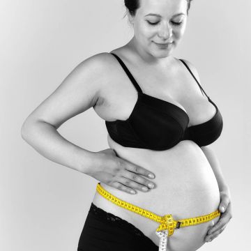 Mutter mit Babybauch misst den Bauchumfang
