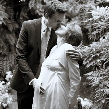 Hochzeitspaar küsst sich im Regen im Park in schwarzweiß