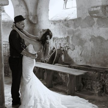 Brautpaar im Pferdestall. Bräutigam mit Hut und lässiger Kleidung, Braut in langem weißen Kleid