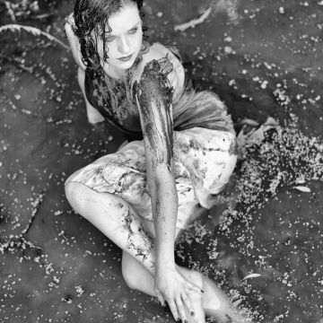Model in weißem Kleid im Schlamm liegend