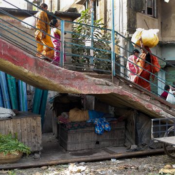 Bunt gekleidete Frauen tragen üppige Waren auf dem Kopf eine Treppe hinauf