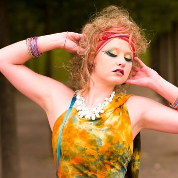 Model stark geschminkt mit geschlossenen Augen und einer Armpose