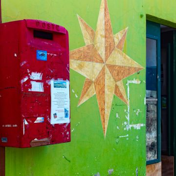 Roter Briefkasten auf grüner Hauswand