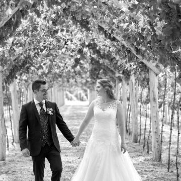 Hochzeitspaar spaziert durch einen Weinrebenbogen in Worms Abenheim