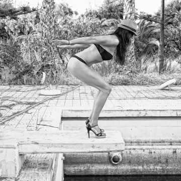Model auf dem Sprungbrett in einer Poolruine
