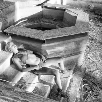 Model liegend auf der Treppe einer Poolruine in schwarzweis